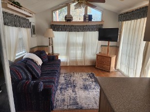 Cozy Living Room Featuring A Couch, A Television, And A Ceiling Fan
