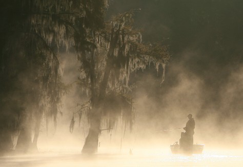 A Man Fishing In A Foggy Atmosphere While Seated In A Small Boat