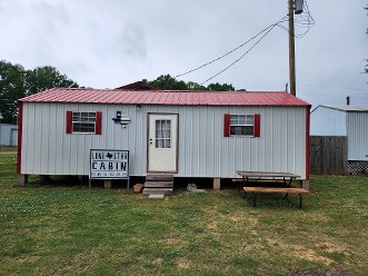 Small White And Red Building Beside A Picnic Table In An Outdoor Setting